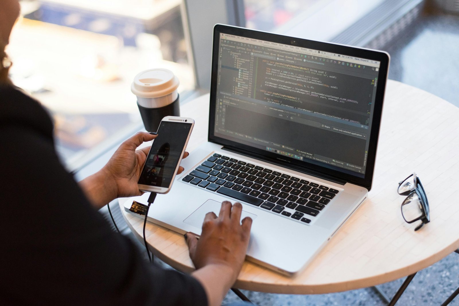 Person working on laptop with smartphone and coffee